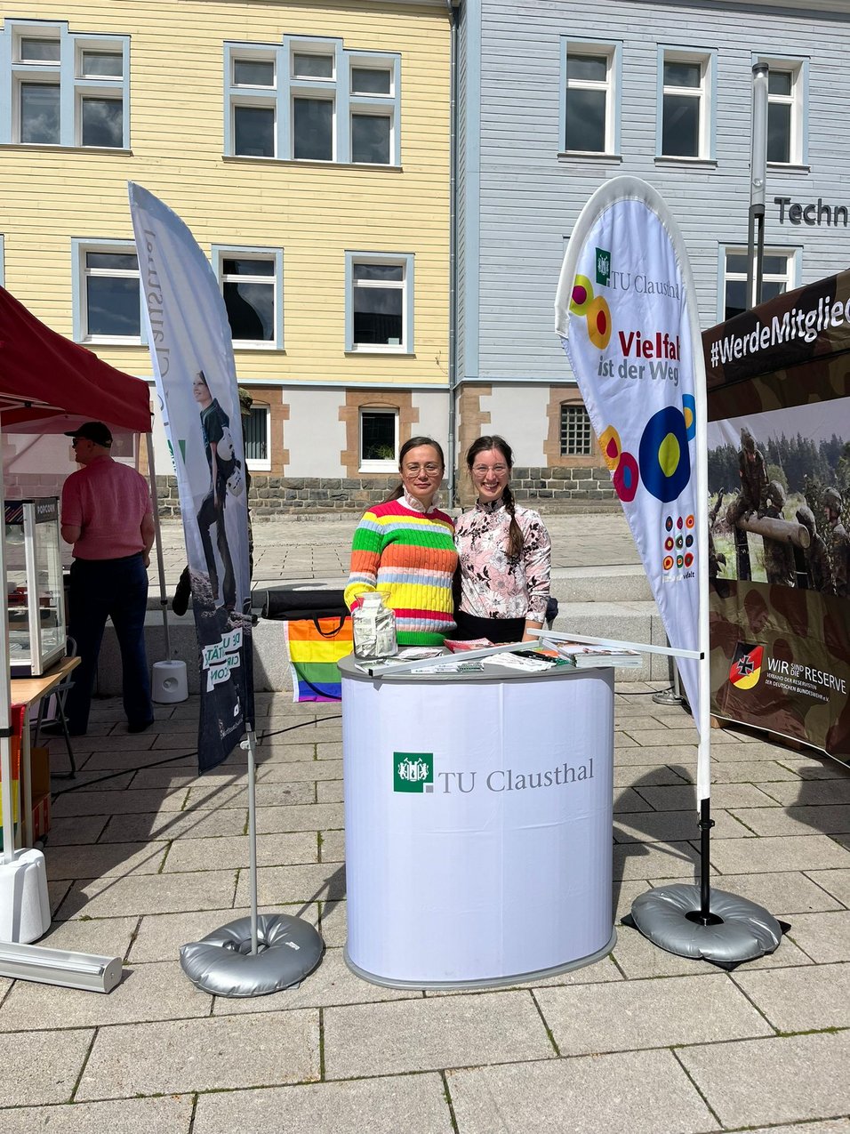 Hier ist ein Informationsstand des Gleichstellungsbüros der TU Clausthal auf dem IDAHOBIT 2024 in Clausthal mit Frau Dr. Schaffel-Mancini und einer Studentin zu sehen.